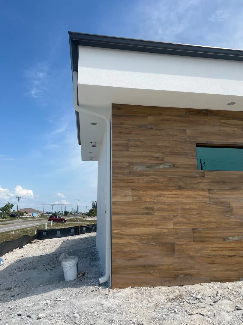Wood composite siding installation with white fascia and black trim on modern home exterior