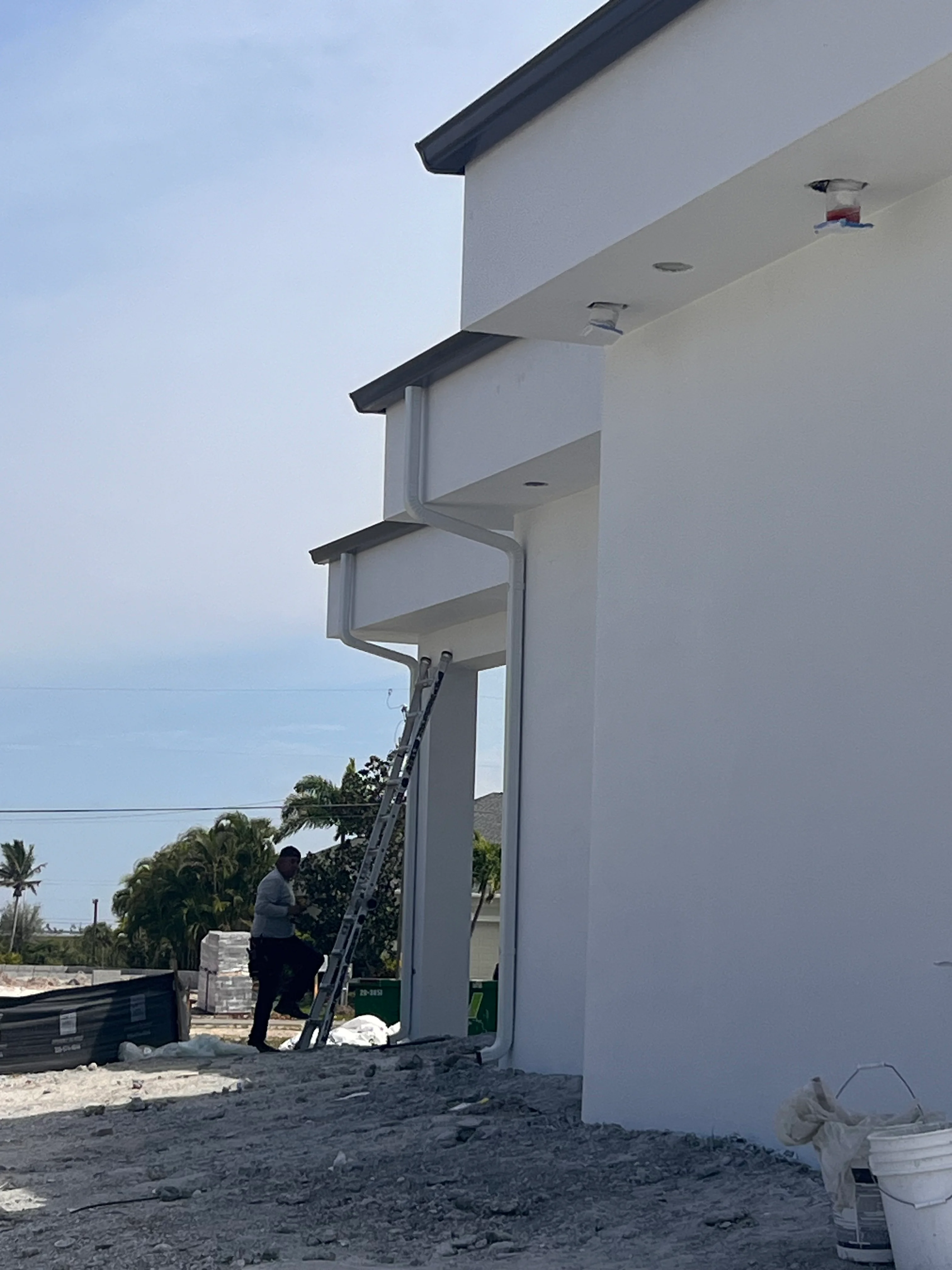 White aluminum soffit and dark metal fascia installed on multi-level residential exterior with ventilation ports