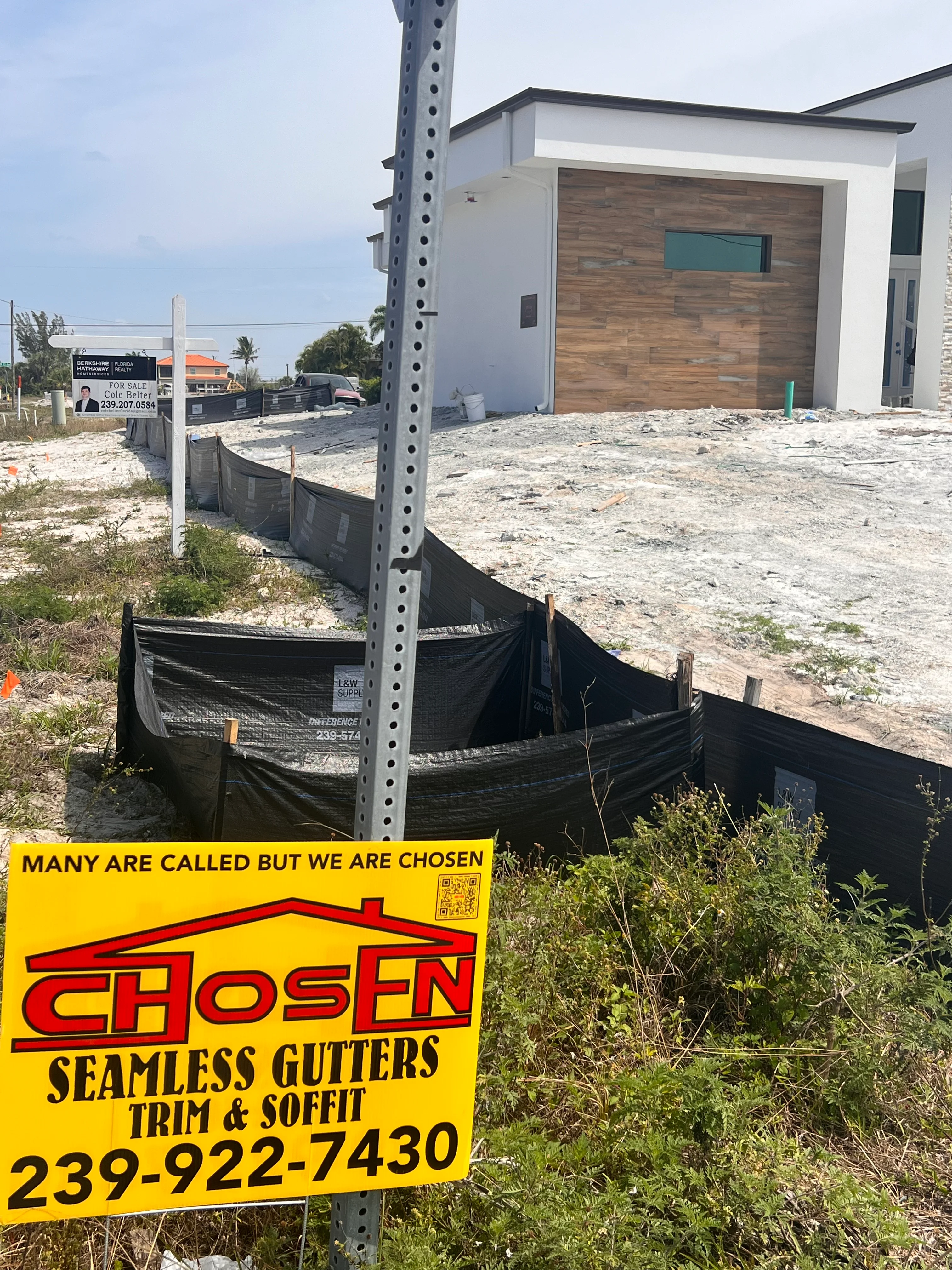 Seamless gutter installation on new construction home with white exterior and wood garage door