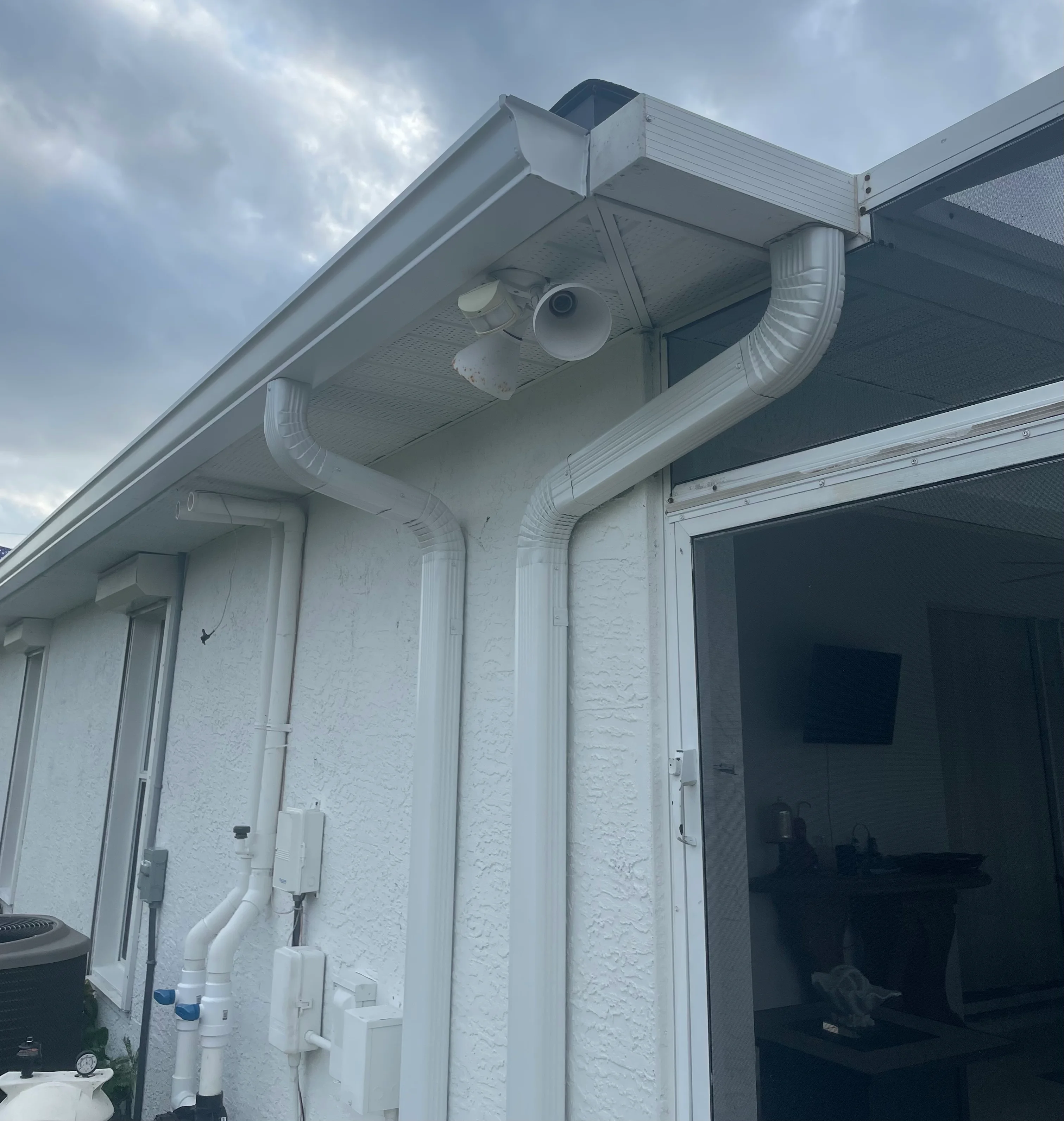 White seamless aluminum gutters with downspouts and brackets installed on residential home