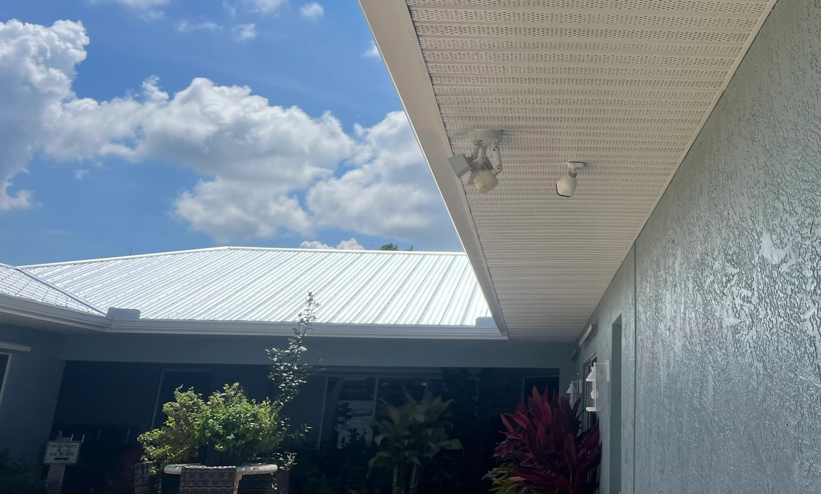 White standing seam metal roof with integrated gutters and downspout on residential structure