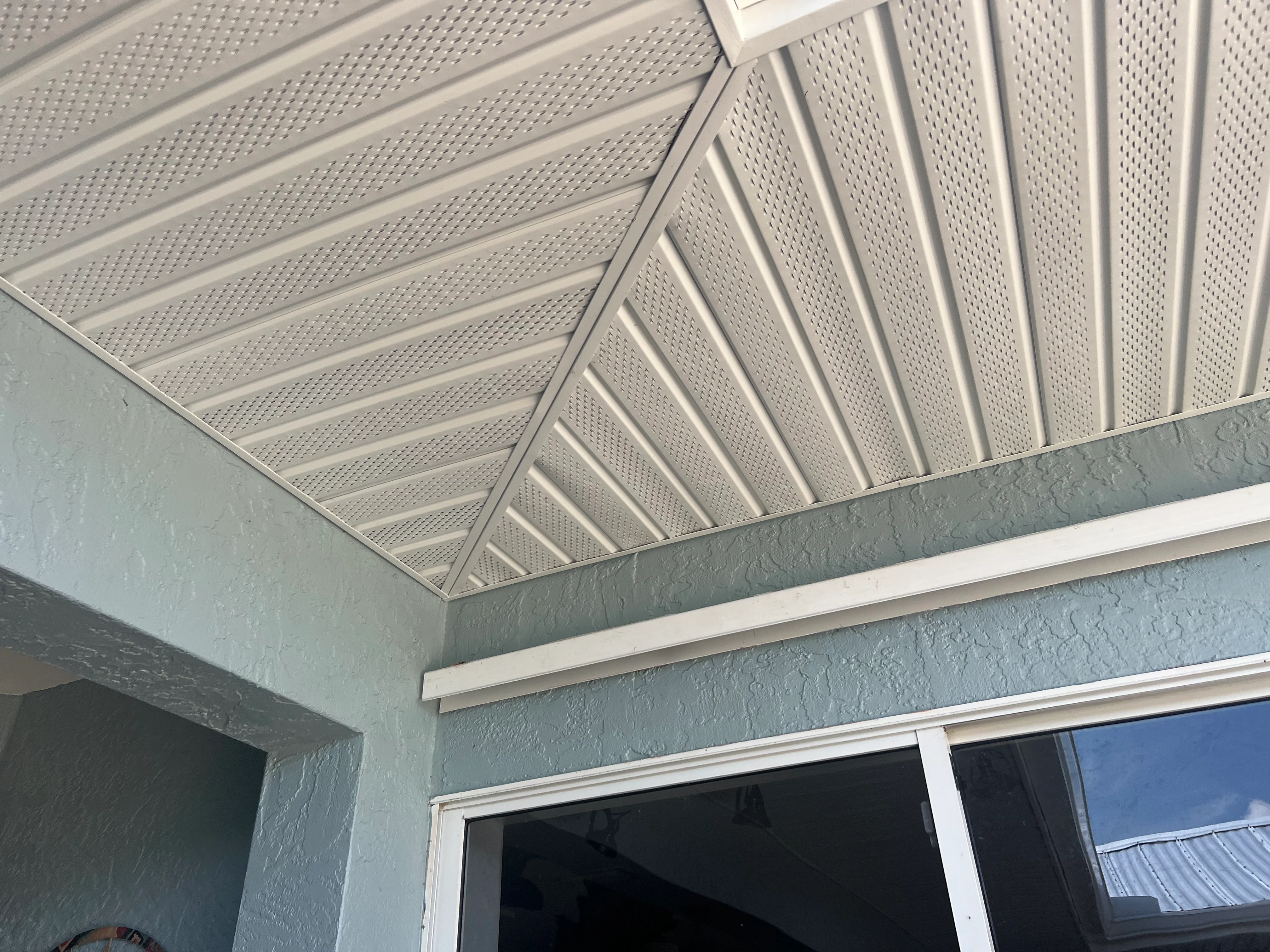 White perforated metal soffit with angled beams and integrated ventilation system