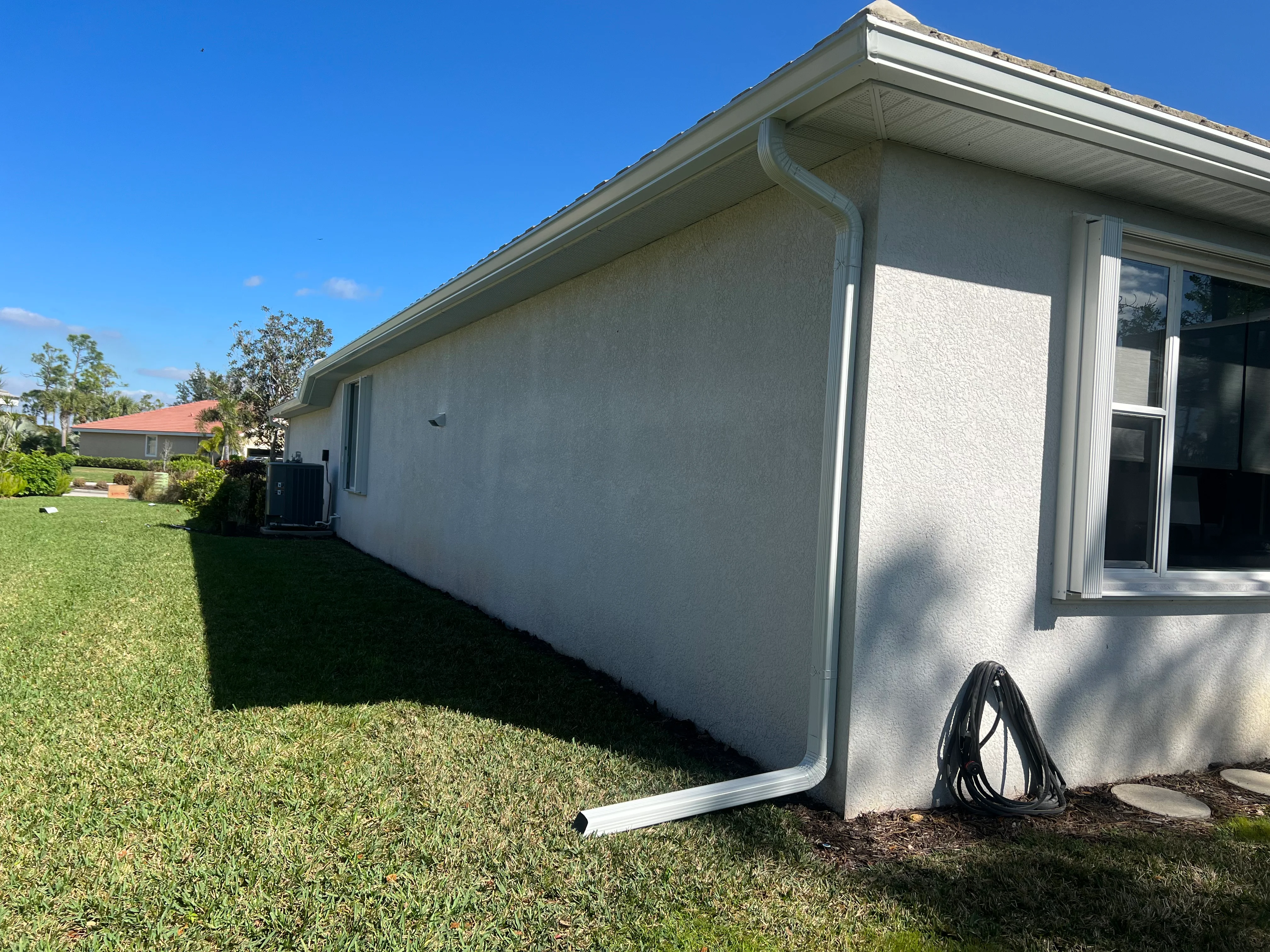 White aluminum gutter system with downspout installed on residential home exterior