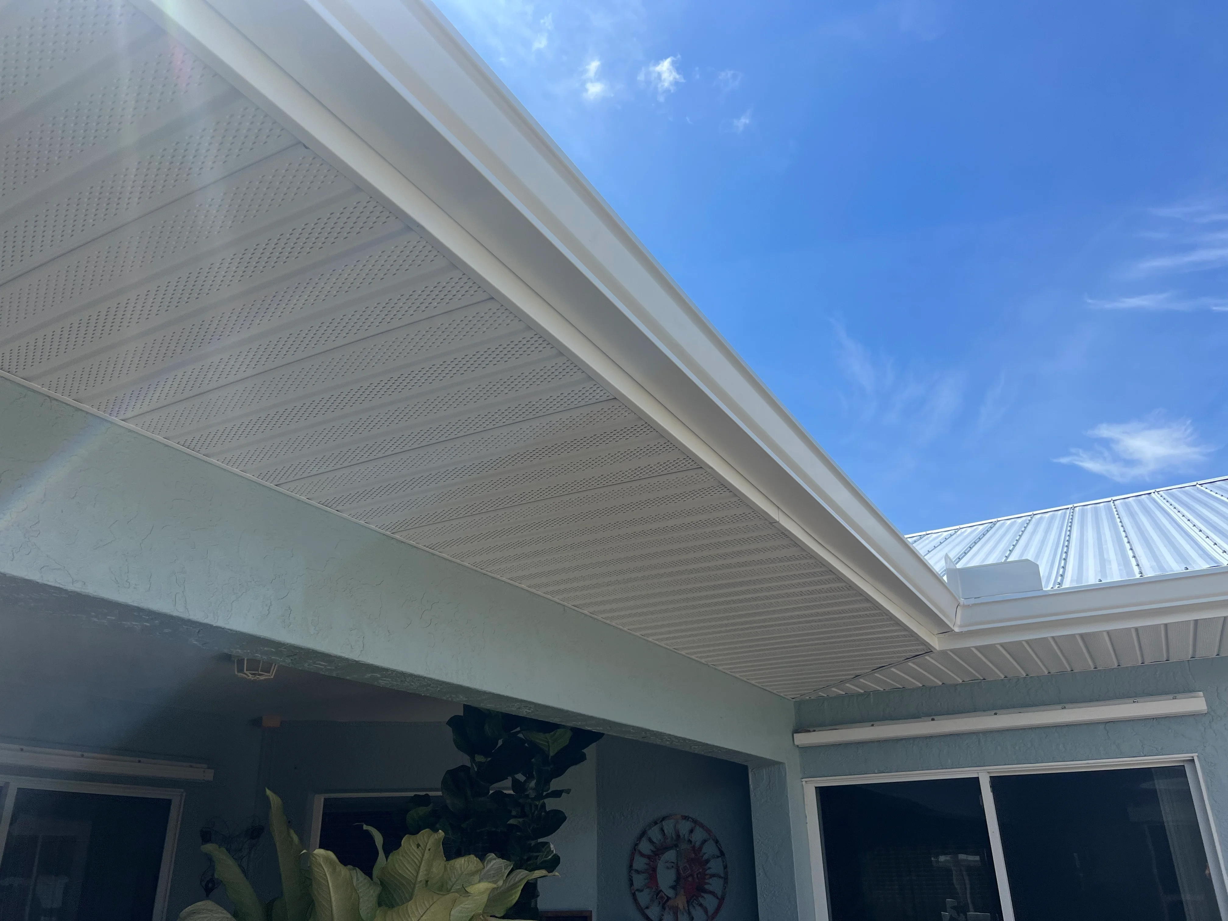White perforated soffit and gutter system installed under residential eave with metal roof trim