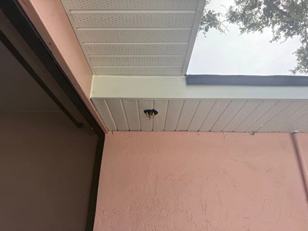 Newly installed white perforated soffit panels and fascia board with ceiling light fixture