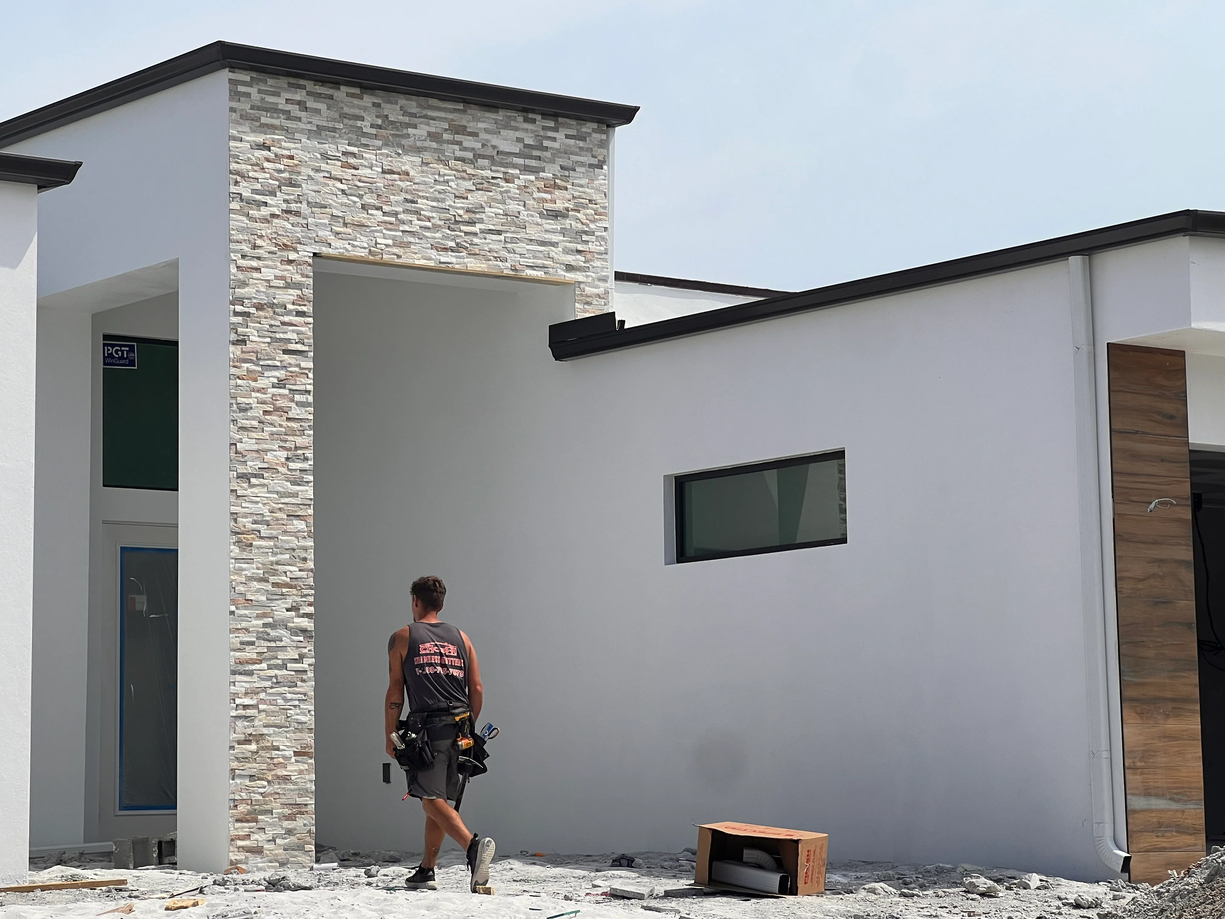 White siding with stacked stone veneer accent wall, black trim, and horizontal window on modern home exterior