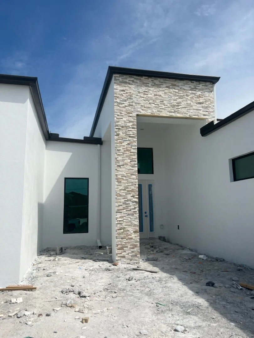 White stucco siding with stacked stone accent column and black trim on modern home exterior