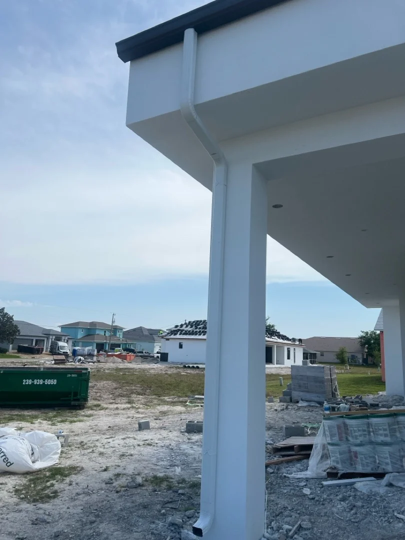 White seamless aluminum gutter and downspout on residential home under construction