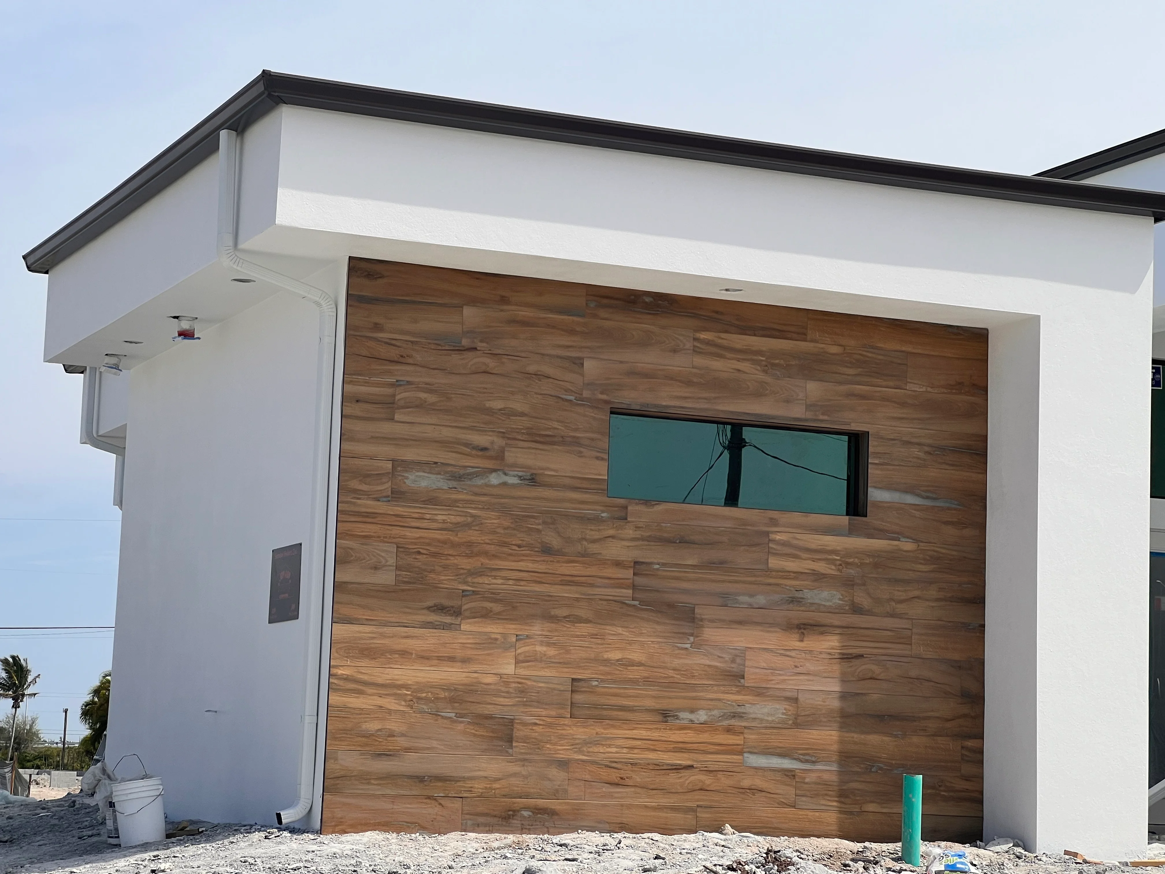 Modern garage with horizontal wood plank siding, white stucco walls, and black metal trim