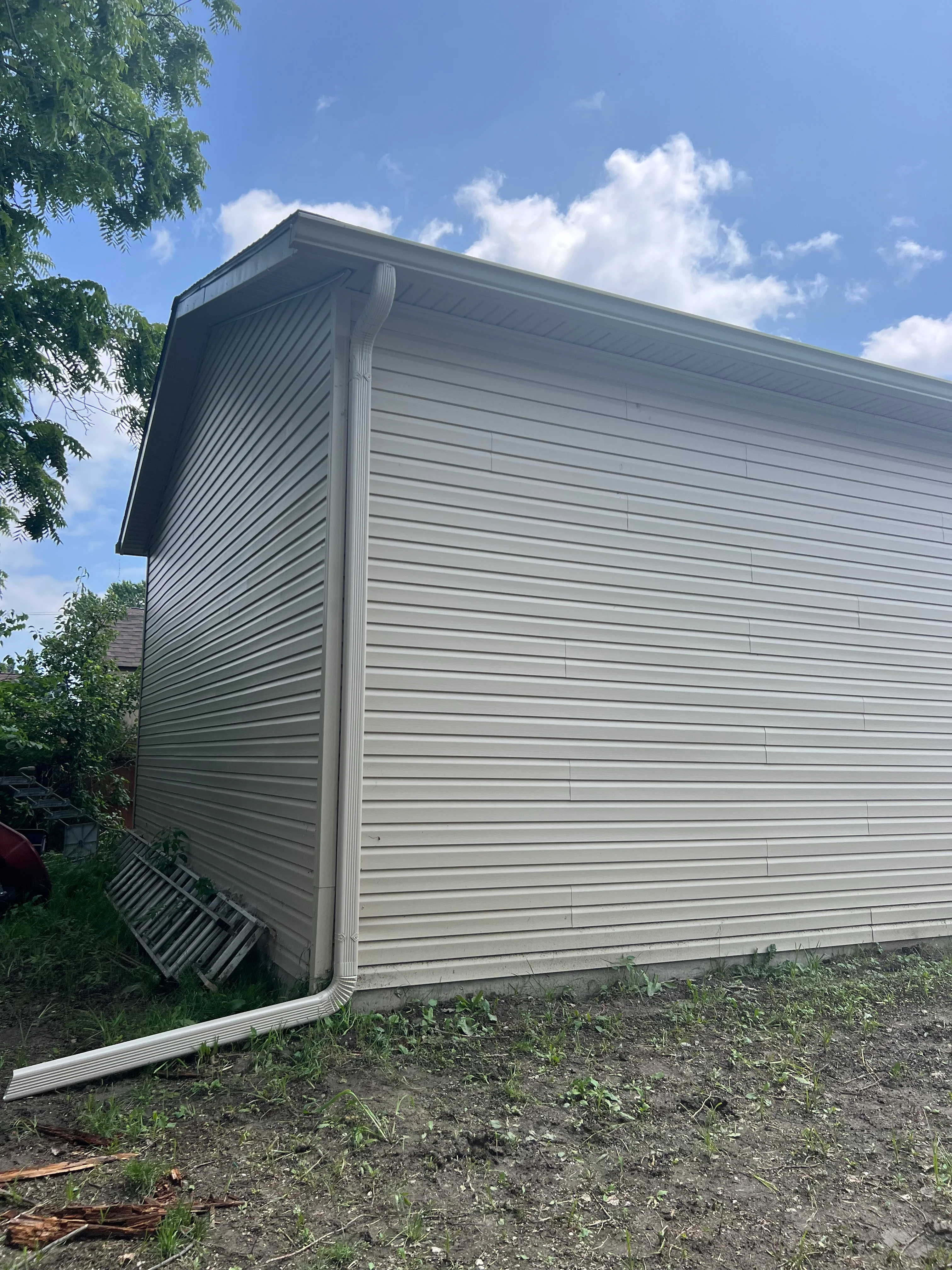 Gray horizontal vinyl siding on residential addition with corner trim and gutters