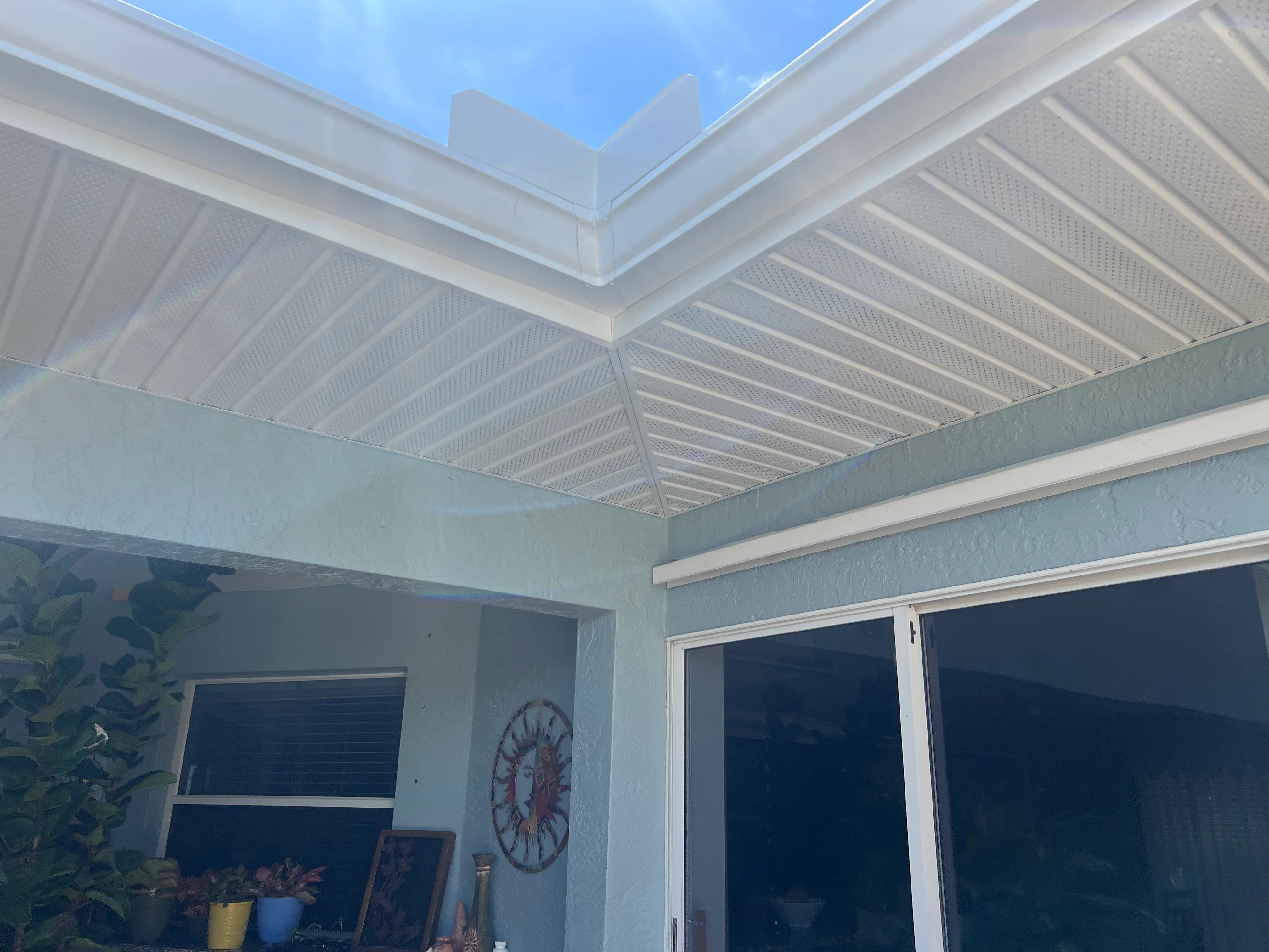 White aluminum patio cover with skylight panels and perforated metal louver slats