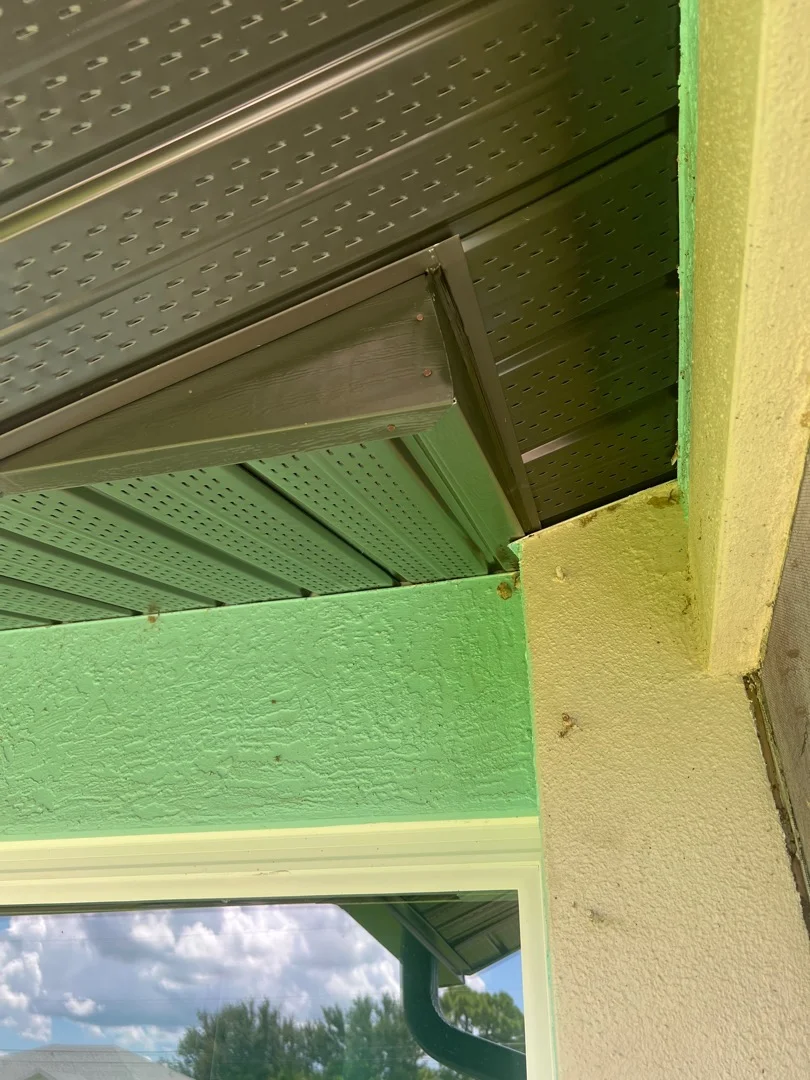 Perforated aluminum soffit and green painted fascia board installation under residential eave