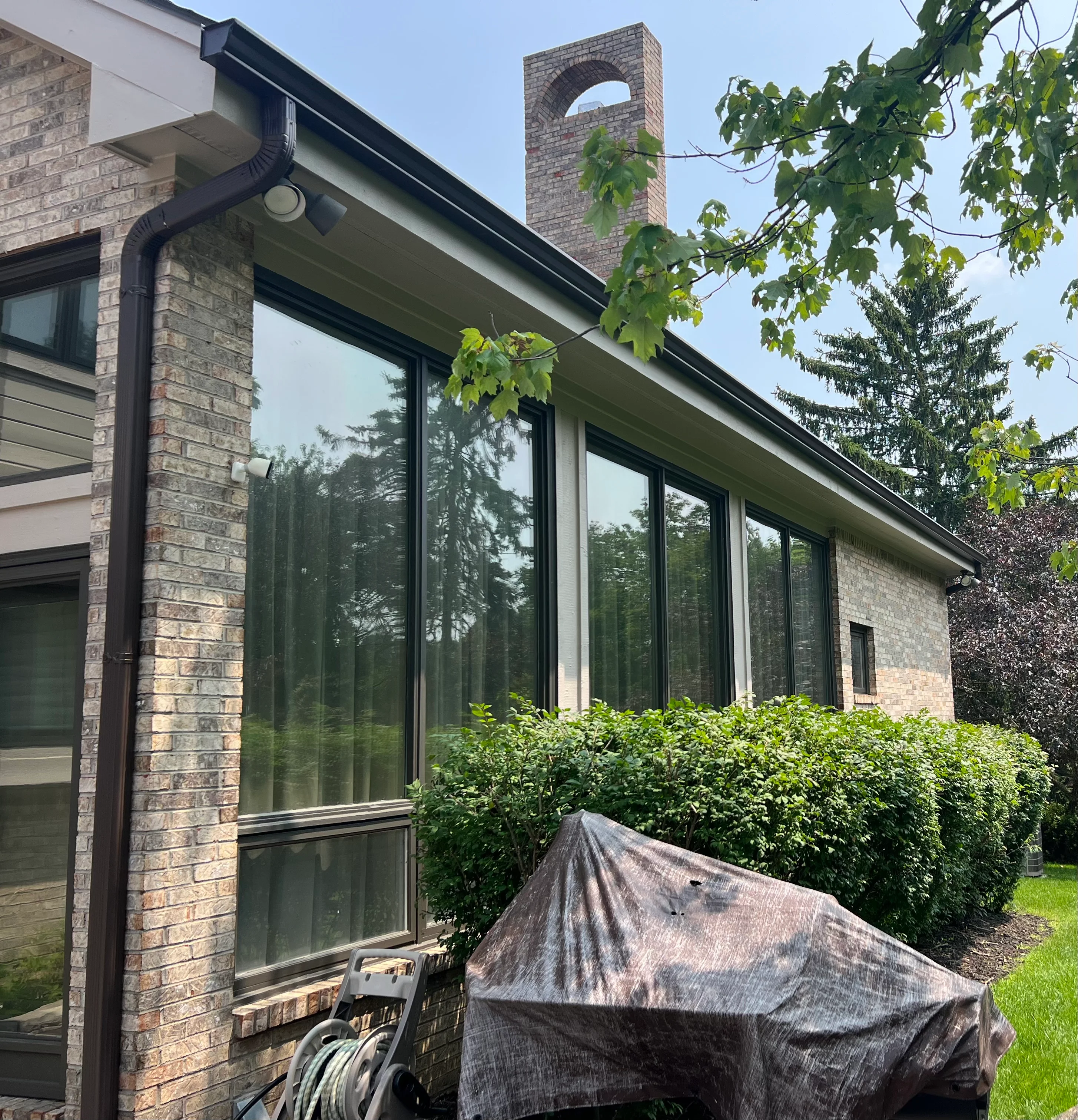 Black aluminum gutters and downspout on brick home with contemporary windows