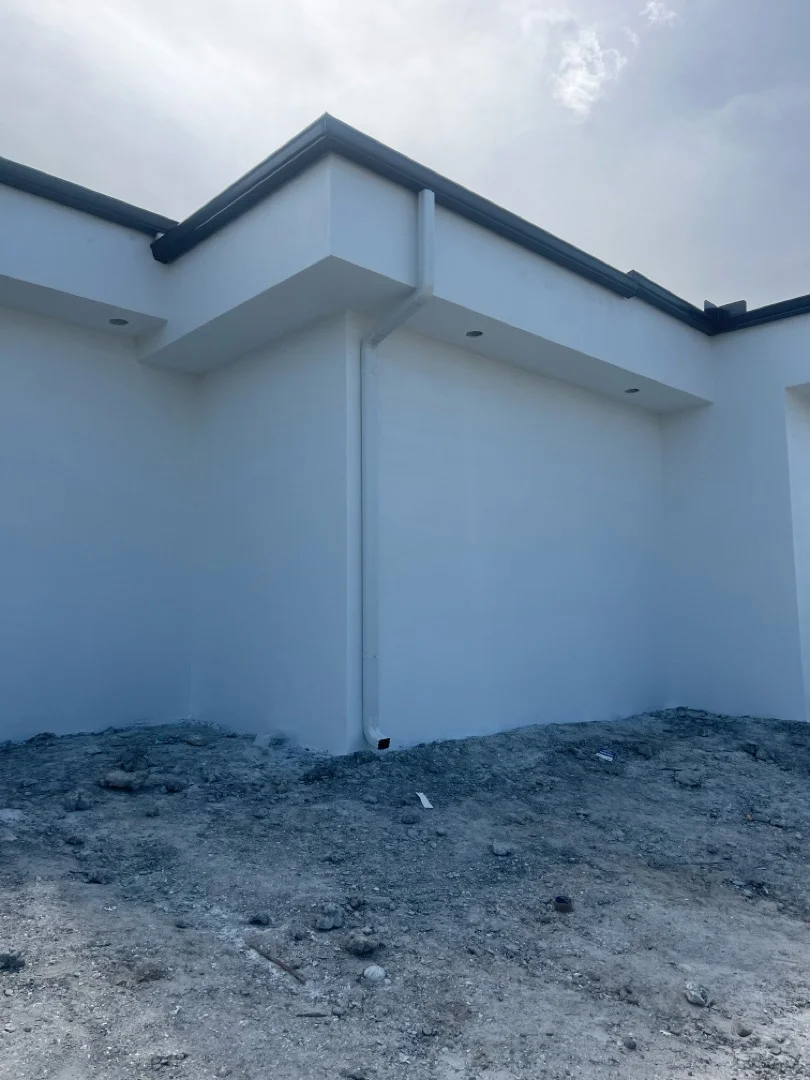 Black aluminum gutter and fascia system on white house exterior with modern roofline
